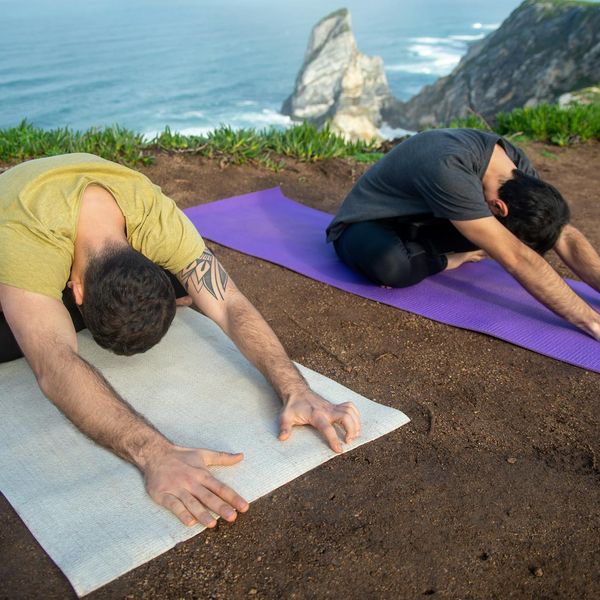 Man in a meditative yoga pose on a rocky overlook.